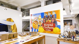Two people sit across from each other in front of Tom Wesselmann’s painting “Great American Nude #53”